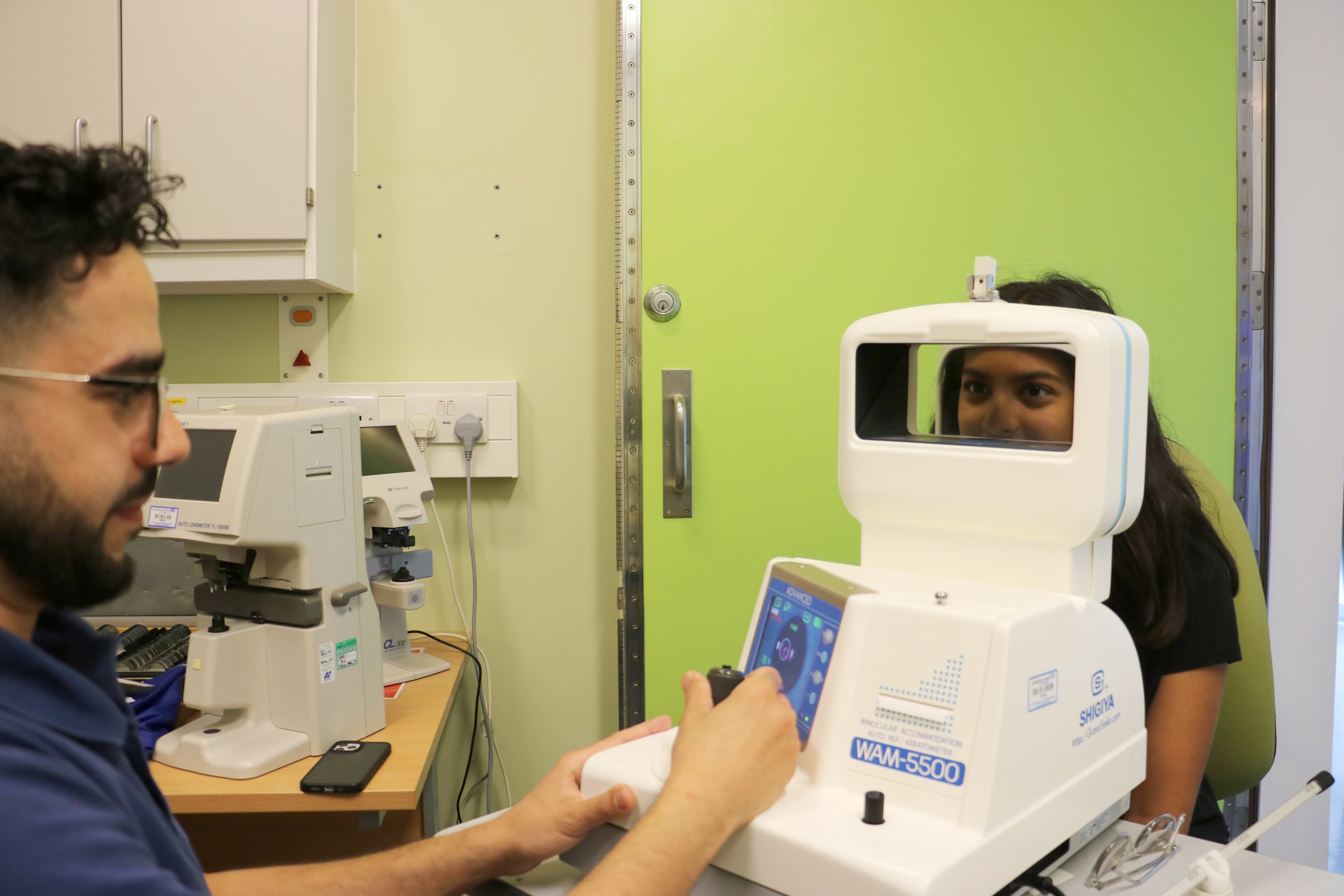 Consultant conducting an eye test on a young person in a hospital consultation room