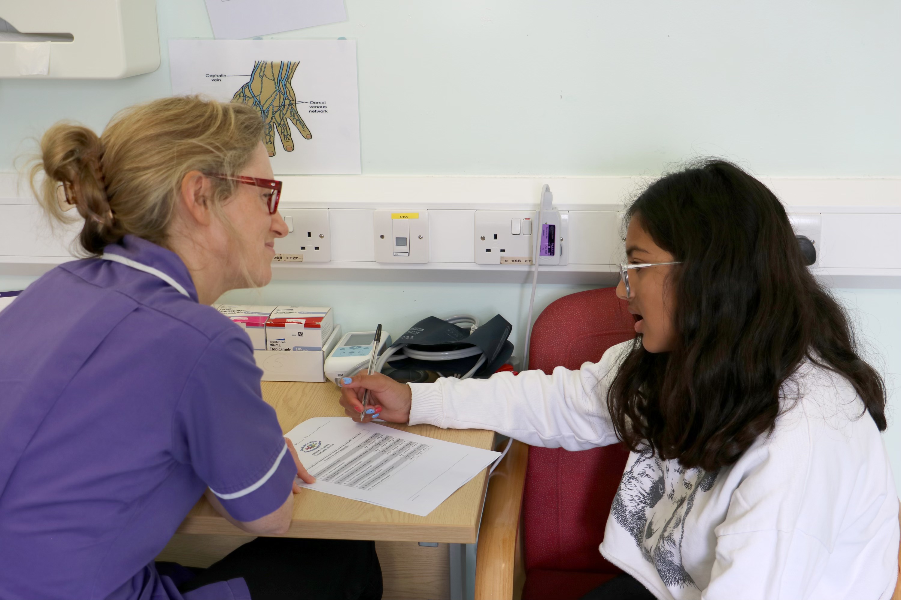 Consultant conducting an eye test on a young person in a hospital consultation room
