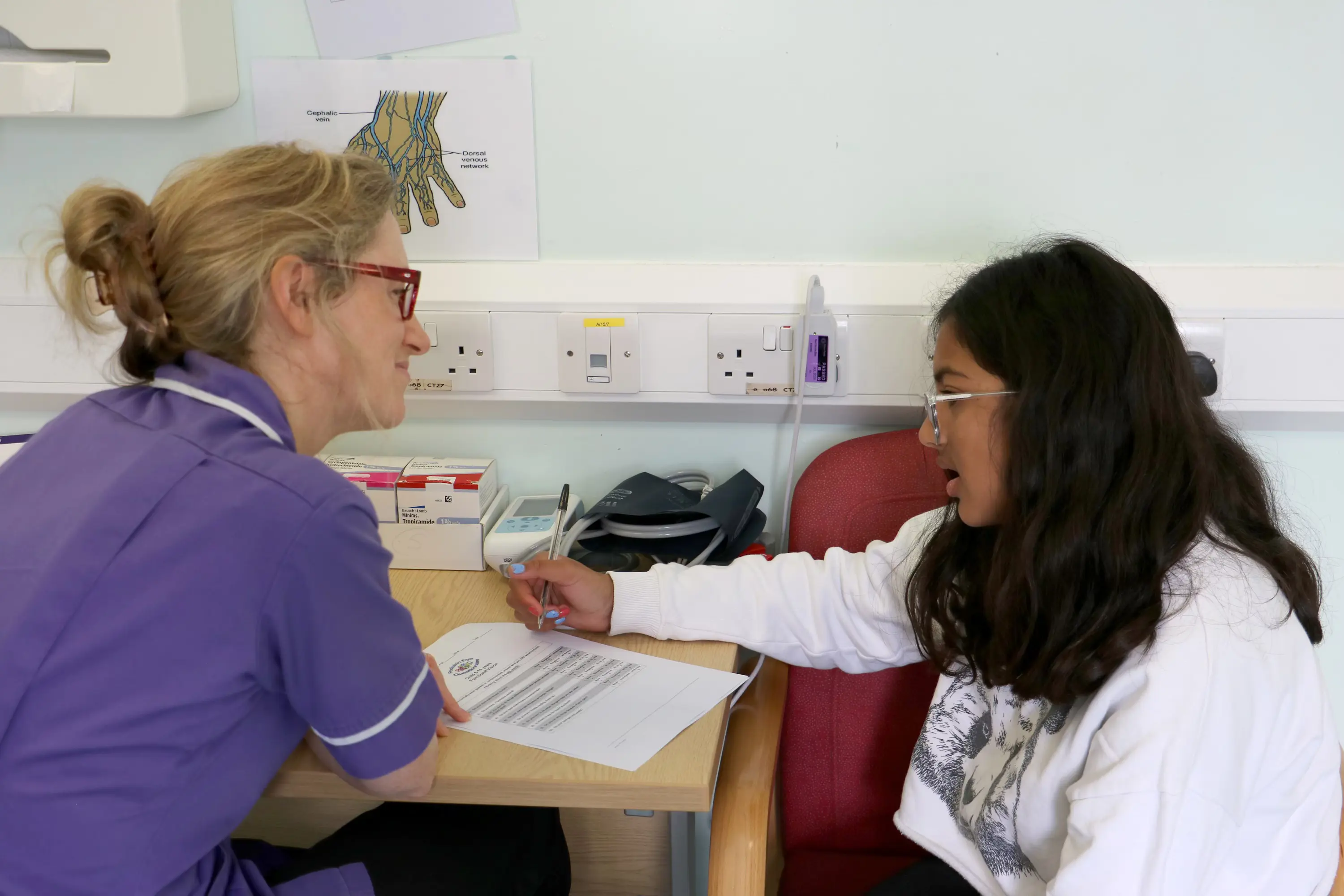 Consultant conducting an eye test on a young person in a hospital consultation room