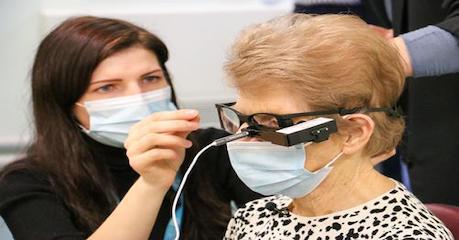 Masked consultant with a patient getting artificial eye fitted