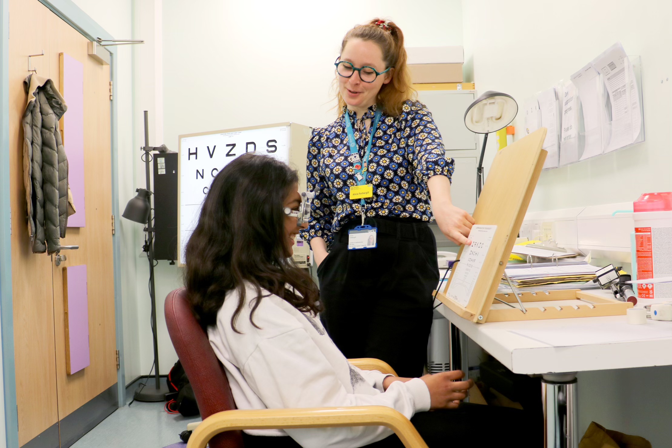 Consultant conducting an eye test on a young person in a hospital consultation room
