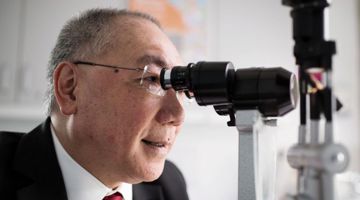 Professor Peng Khaw  looking into a microscope