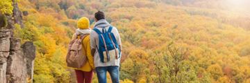 Two people looking at the trees from a top of the hill