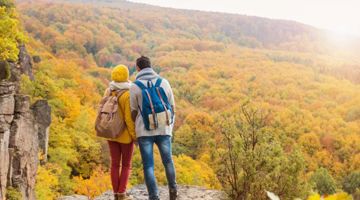 Two people looking at the trees from a top of the hill