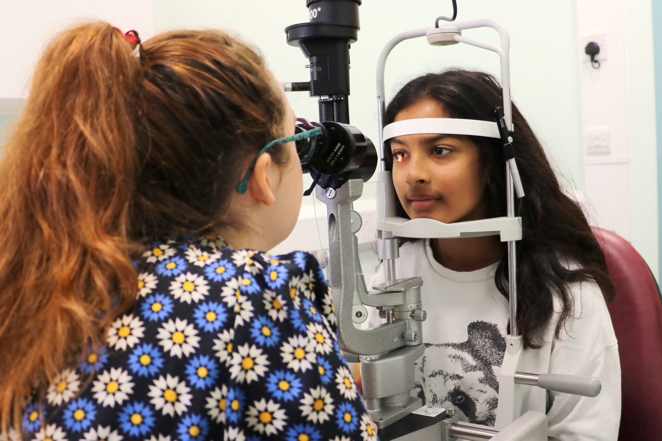 Consultant conducting an eye test on a young person in a hospital consultation room