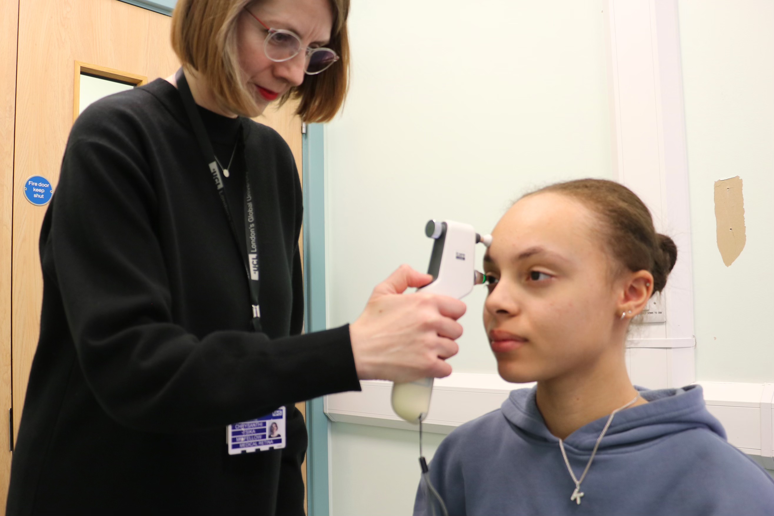 Consultant conducting an eye test on a young person in a hospital consultation room