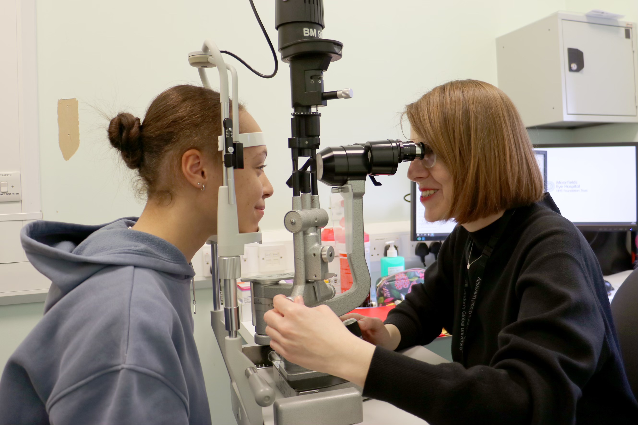 Consultant conducting an eye test on a young person in a hospital consultation room