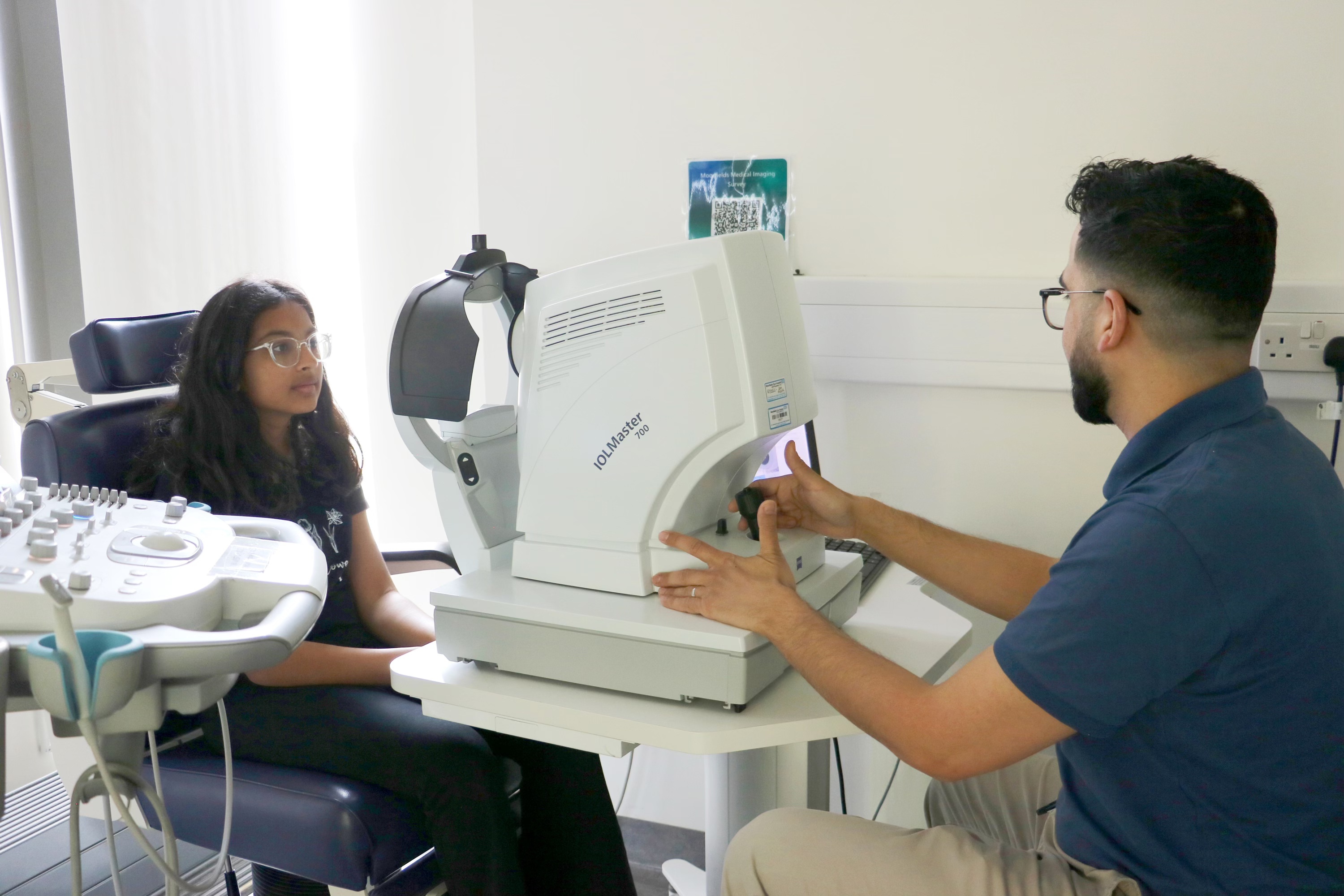 Consultant conducting an eye test on a young person in a hospital consultation room