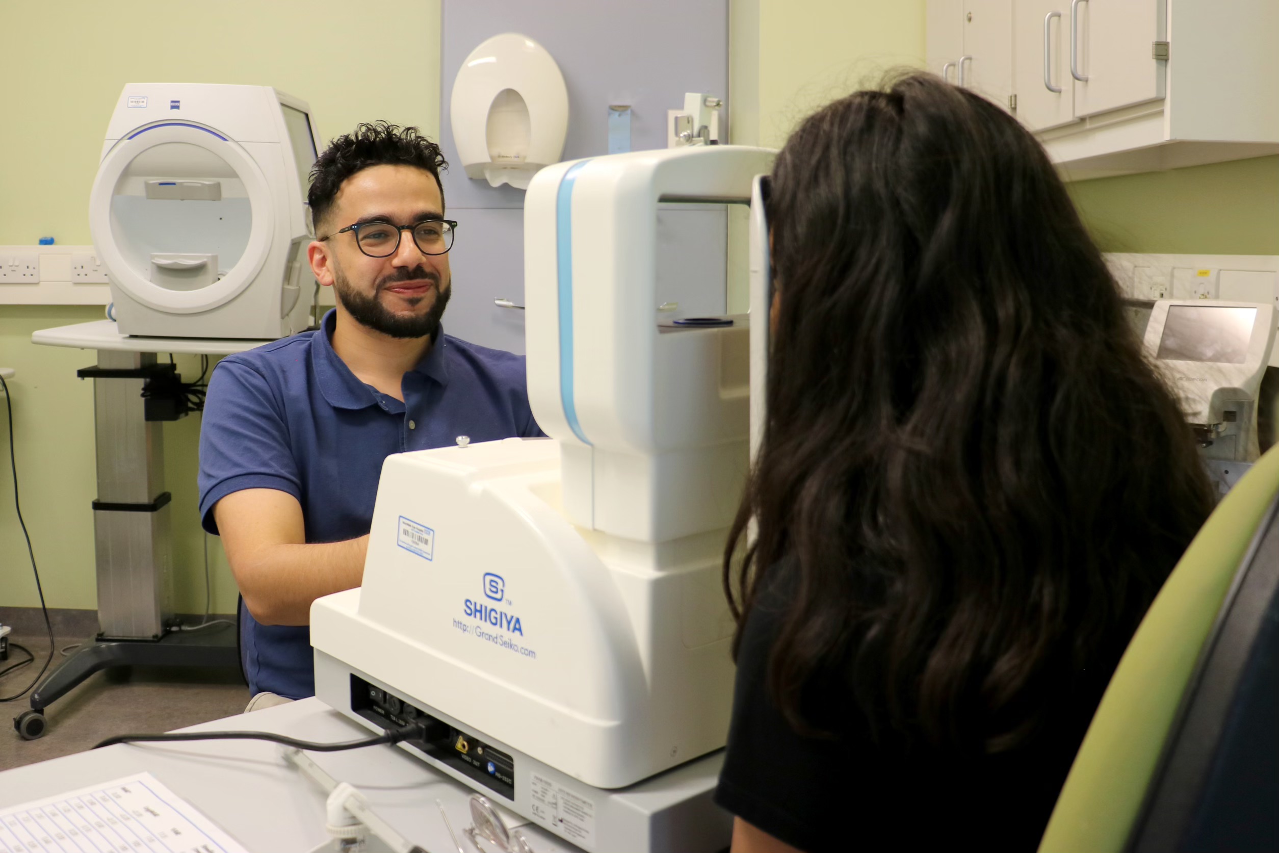 Consultant conducting an eye test on a young person in a hospital consultation room