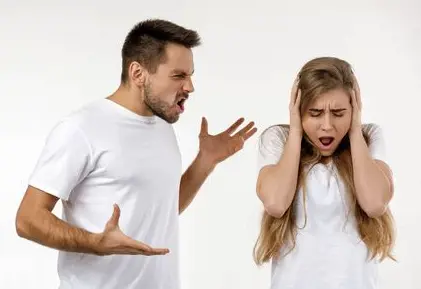 Person with hands up and shouting at a person with their hands over their ears and head turned down