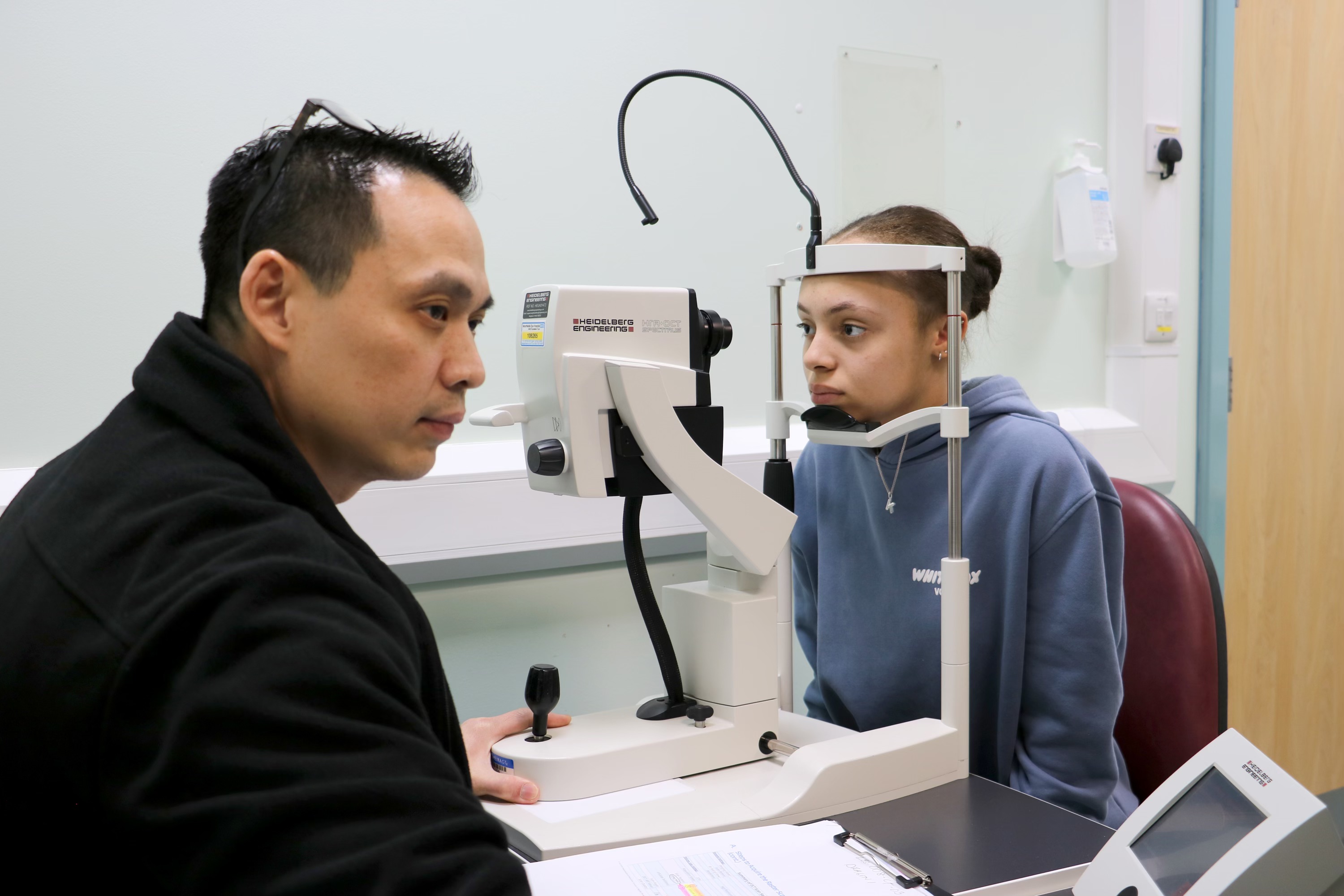 Consultant conducting an eye test on a young person in a hospital consultation room