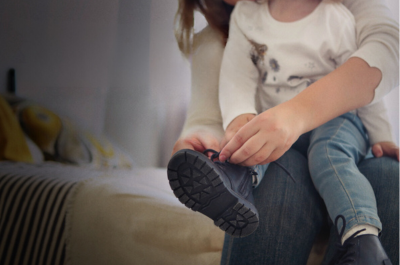 A woman holding a child and helping them with the shoelaces