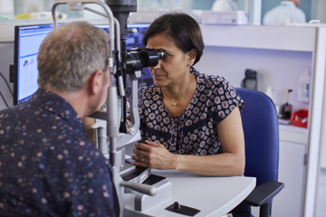 Patient being examined through slit lamp by Moorfields clinician.