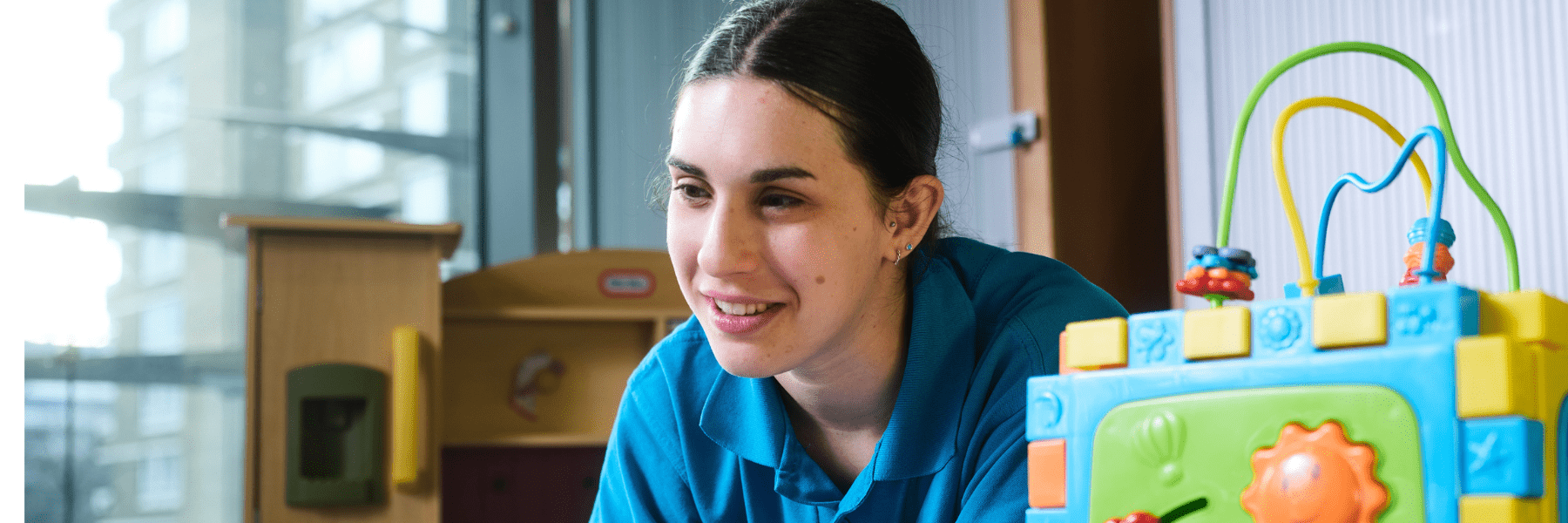 Staff member giving care in the paediatric centre, Jemma with a blue toy