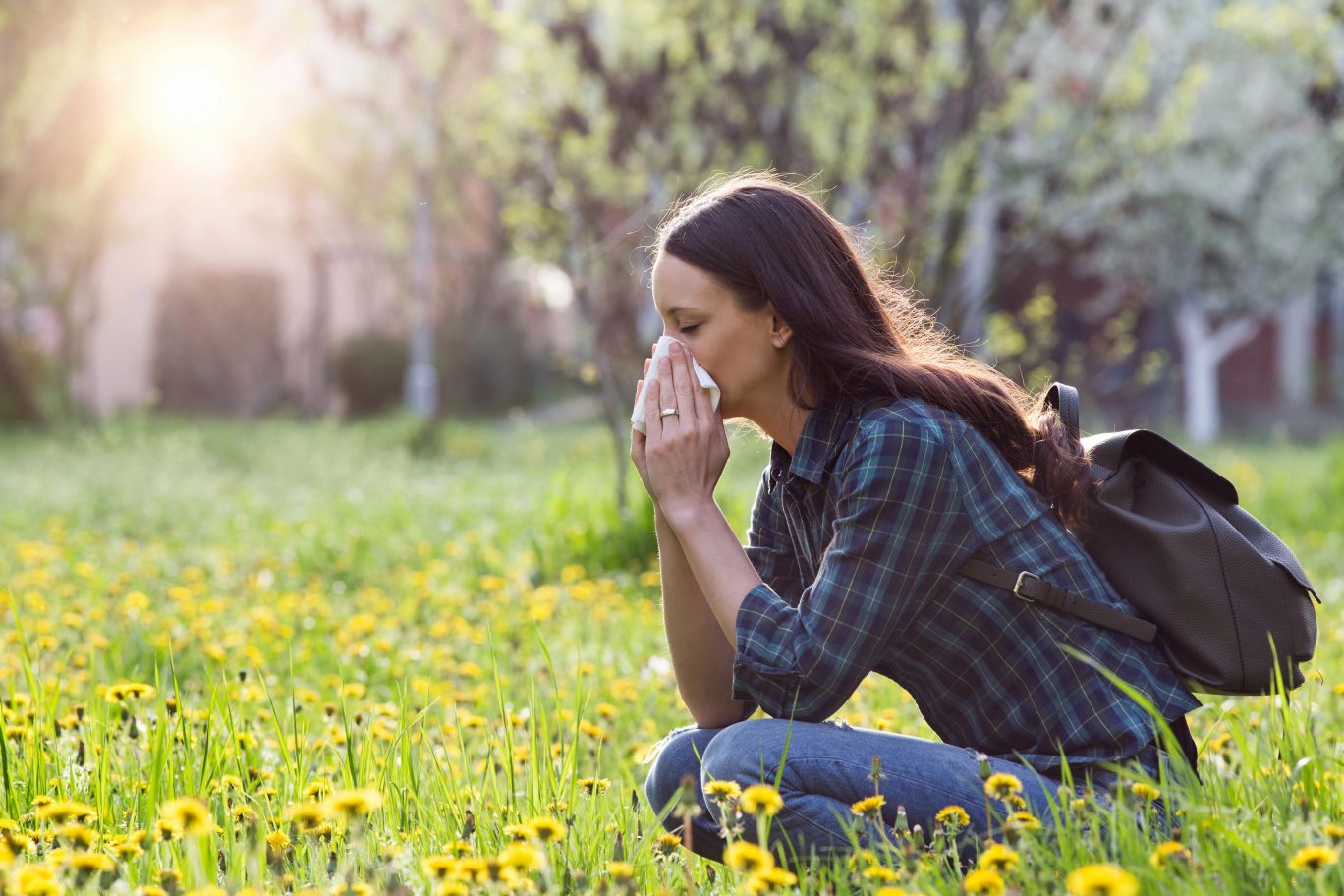 A young woman outside sneezing